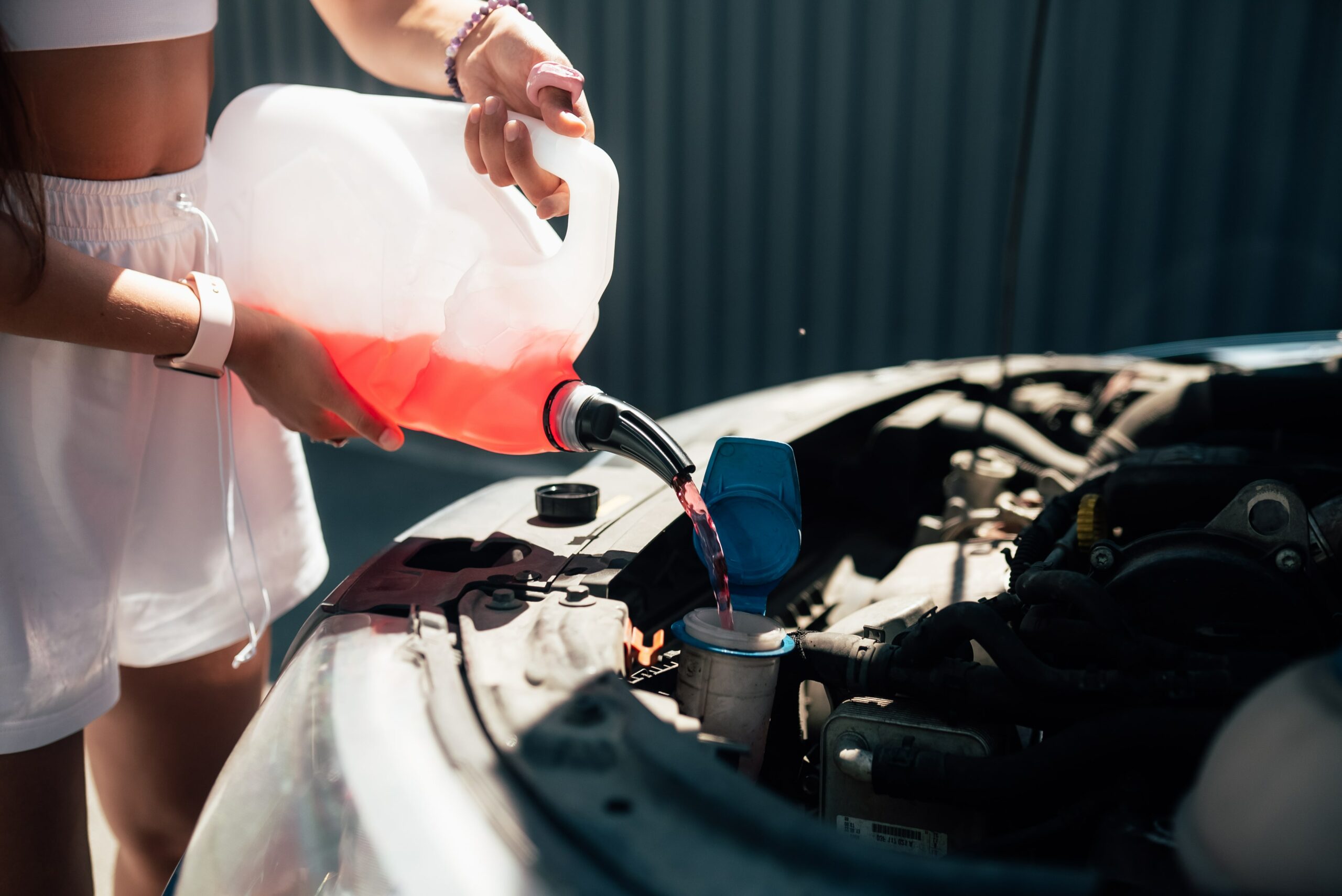 Mujer joven poniendo líquido anticongelante para el coche